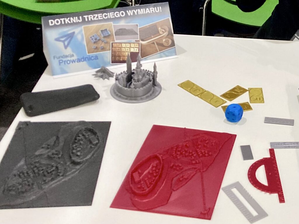 TargiOpole4 Targi Dostępności. Na stole znajdują się baner, makiety, akcesoria i domino.