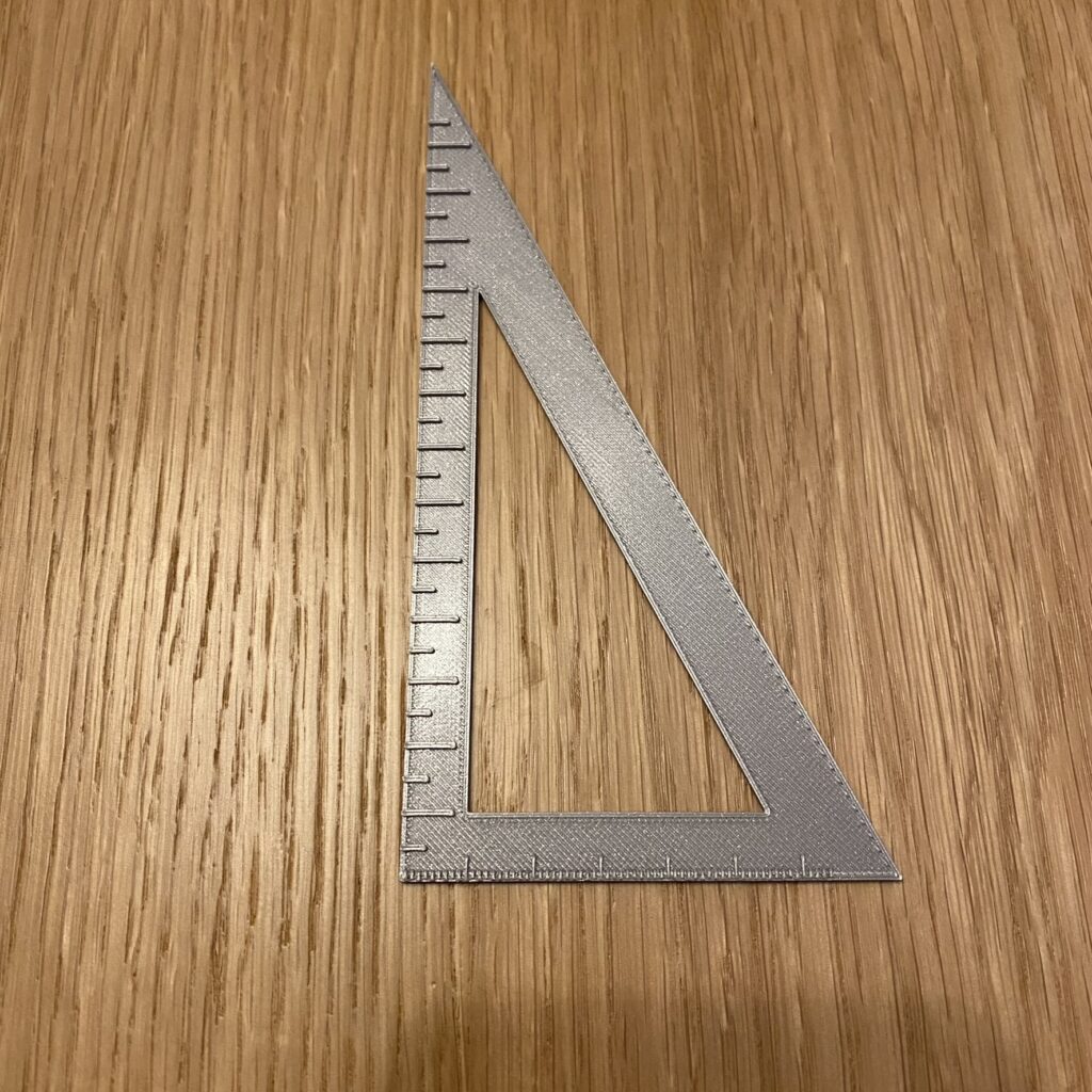 ekierka, PLA srebrne Srebrna ekierka prostokątna. Na krótszej przyprostokątnej znajduje się linijka z przedziałką co milimetr, na dłuższej, co pół centymetra.