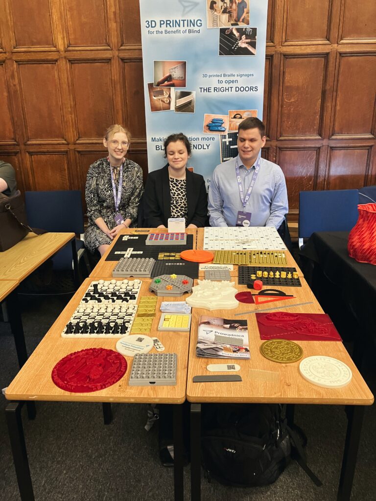 Dawid, Julita i Magda przy swoim stanowisku. Widać część banera fundacji i stół z wydrukami