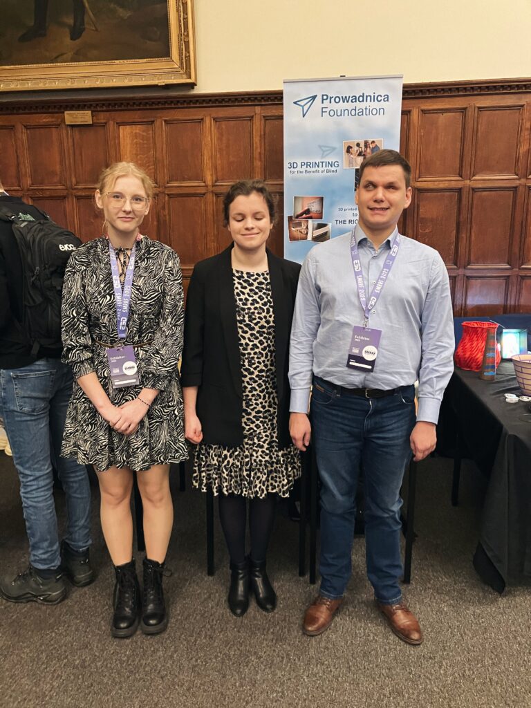 Dawid, Julita i Magda stoją na tle banera fundacji